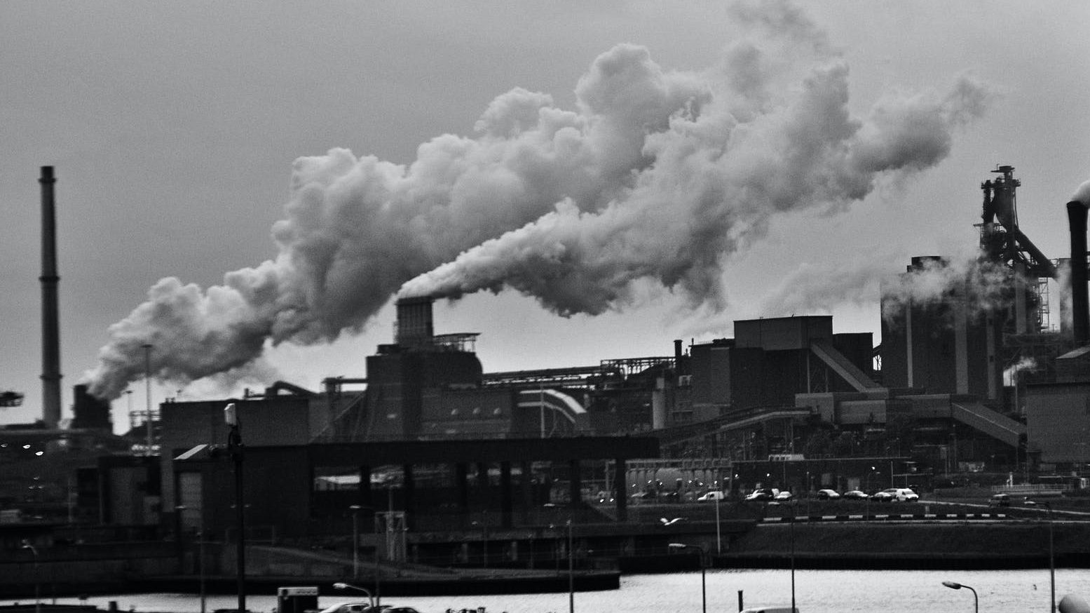 grayscale photography of locomotive train beside factory