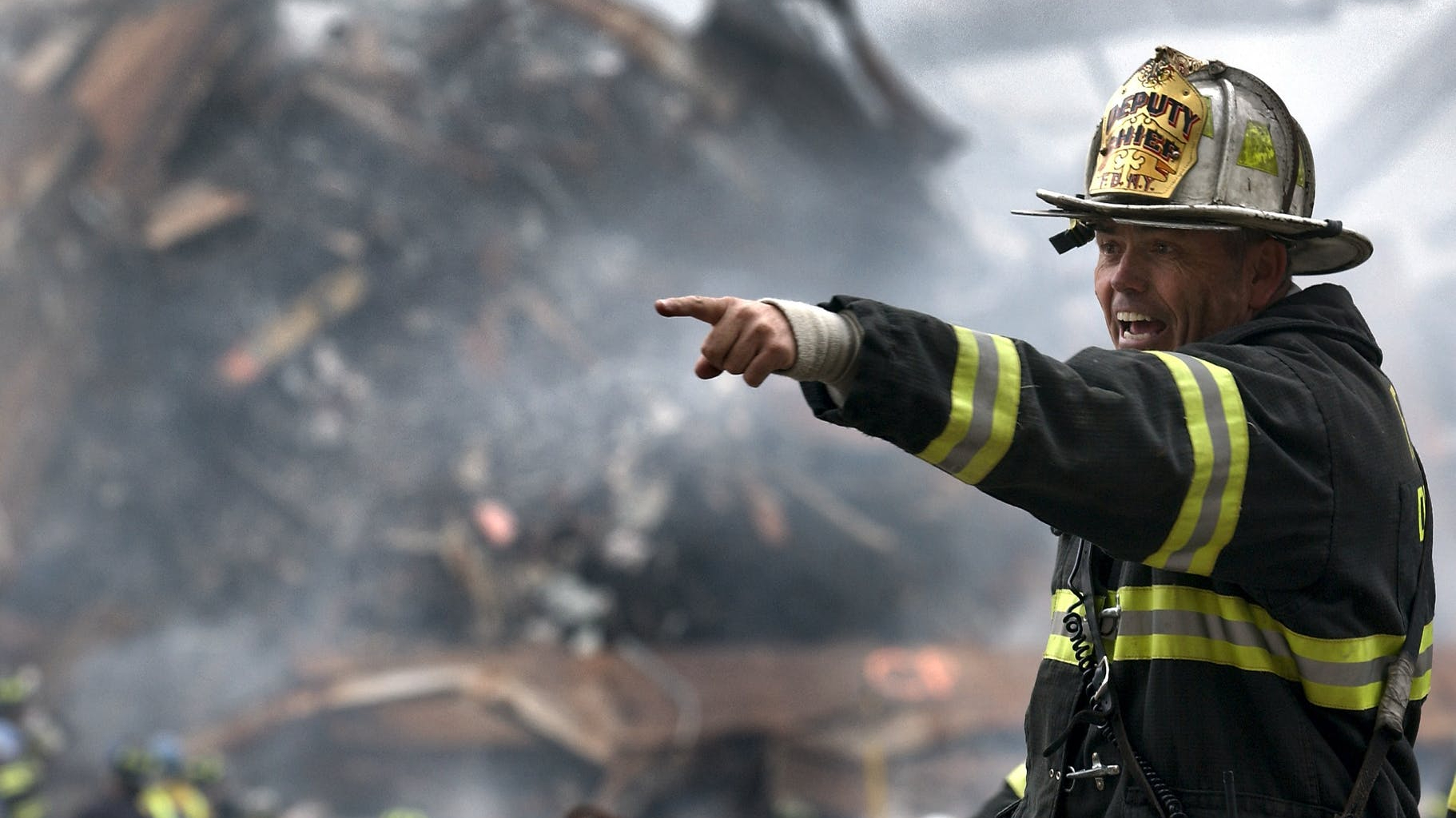 fire fighter wearing black and yellow uniform pointing for something