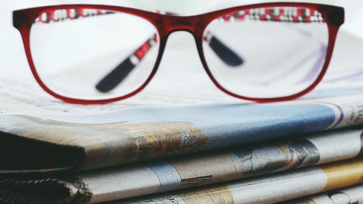 red framed eyeglasses on newspapers