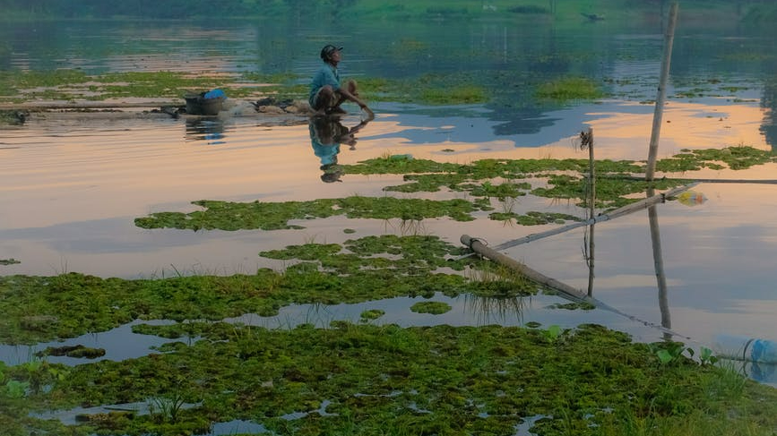 boy sitting on a rock near body of water