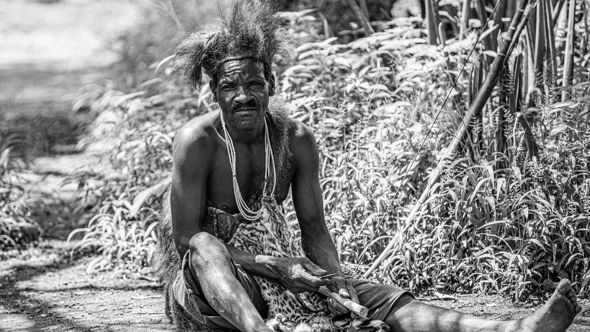 grayscale photo of topless man sitting on ground