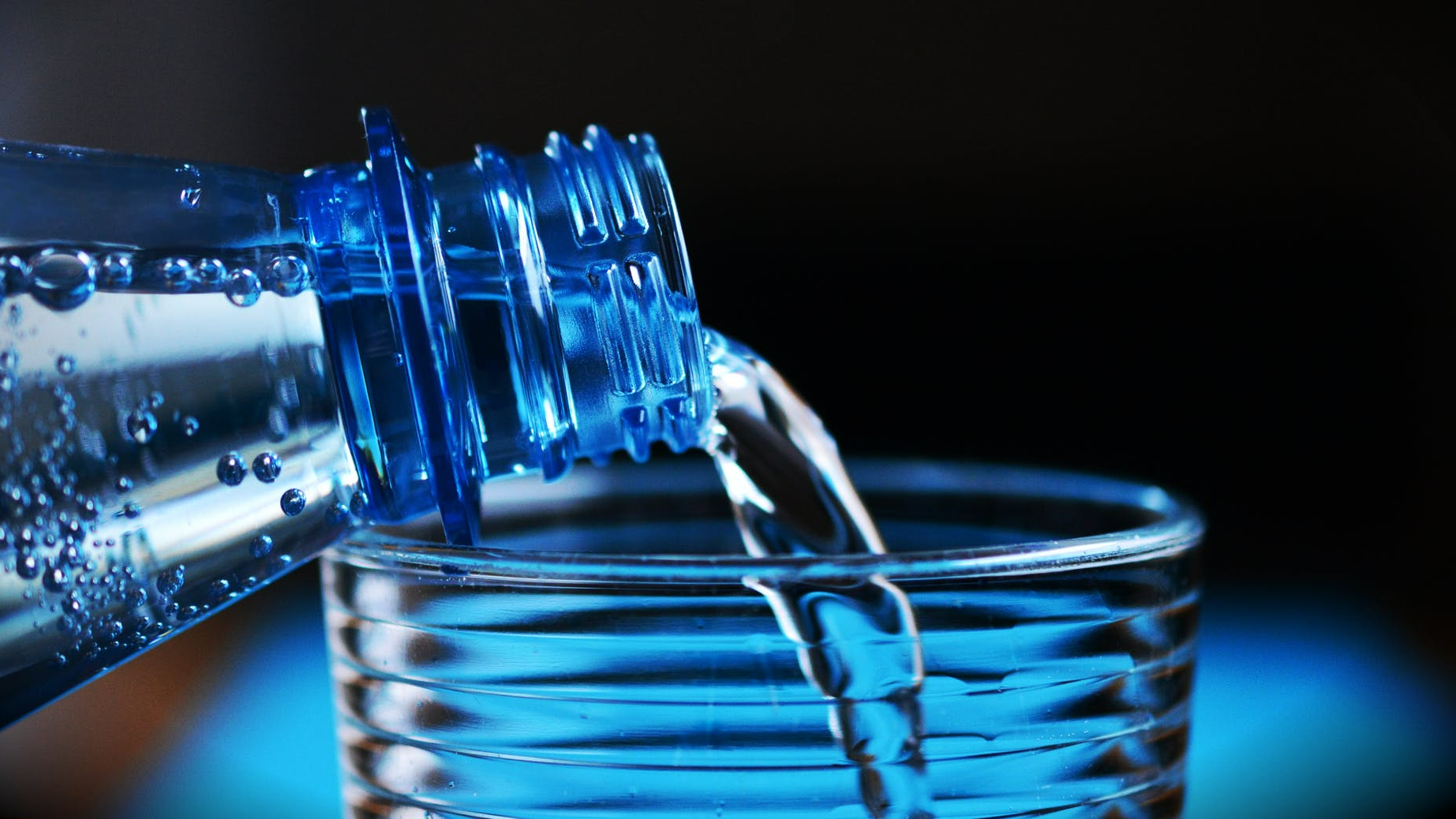 close up of bottle pouring water on glass