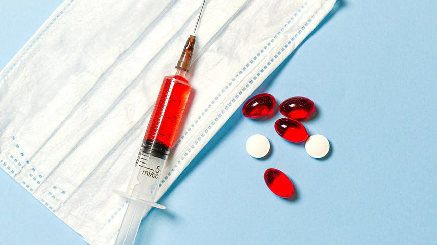 syringe and pills on blue background