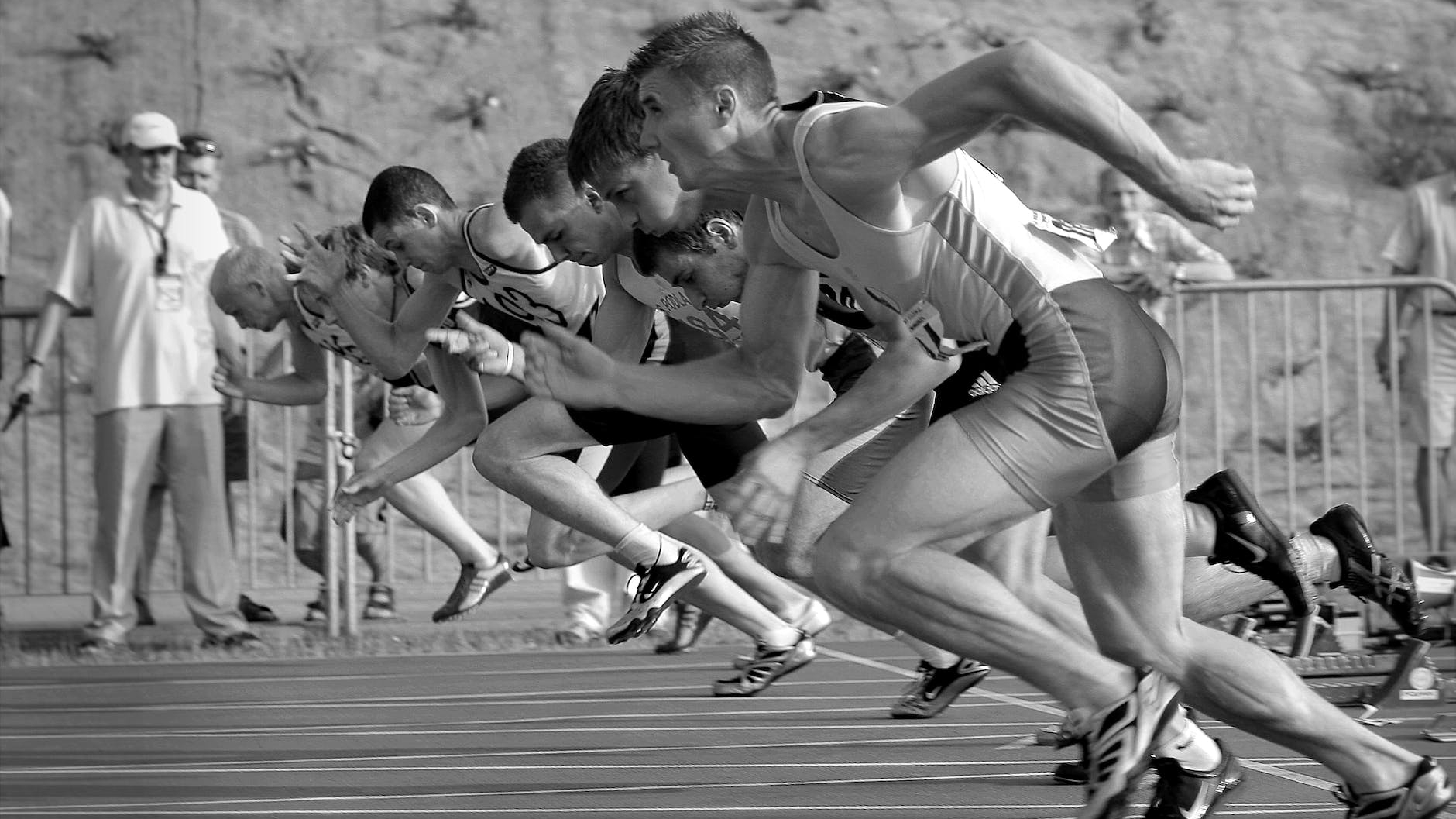 athletes running on track and field oval in grayscale photography