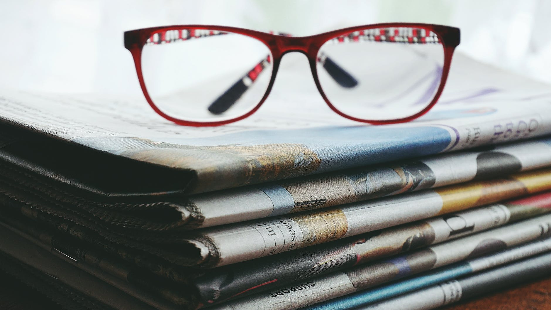 red framed eyeglasses on newspapers